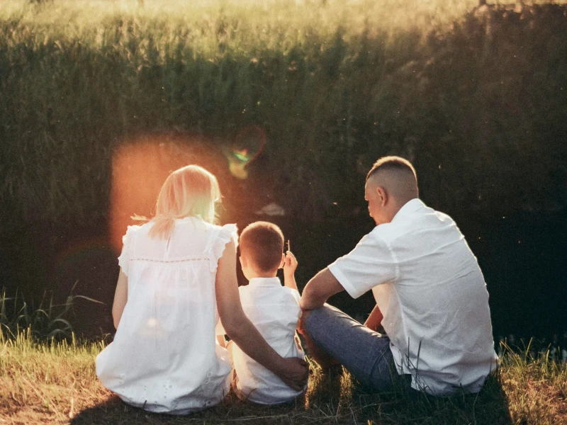 Eltern mit Kind sitzen auf einer Wiese